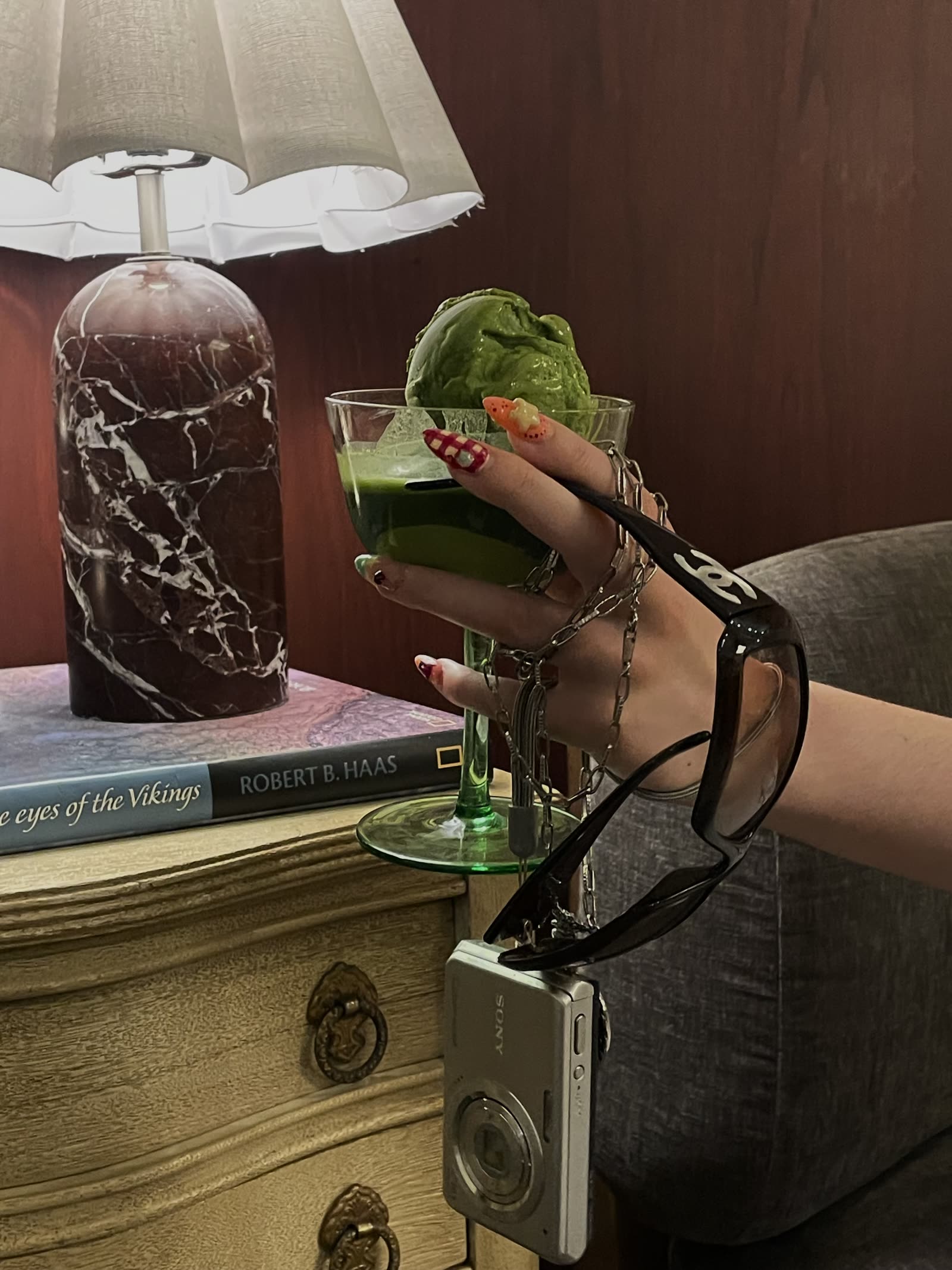 A gingham and star set on a hand holding a matcha dessert, with sunglasses and a compact camera